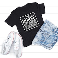 a black t - shirt that says i'm a nurse not a magician